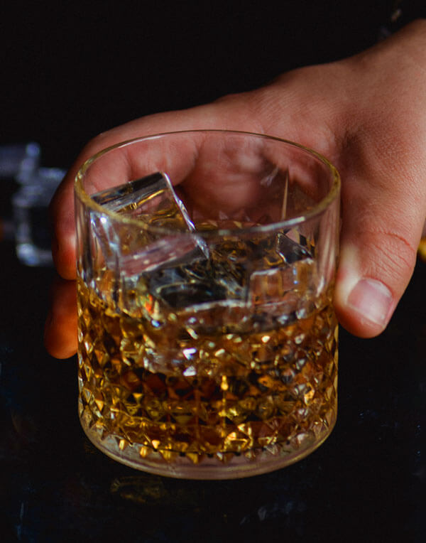 A whiskey cocktail on the bar top in low amber light